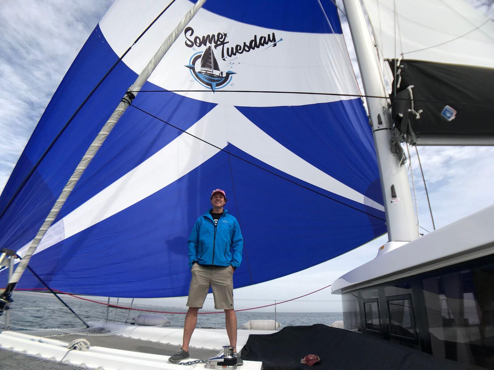 Steve standing in front of Some Tuesday&rsquo;s blue sail
