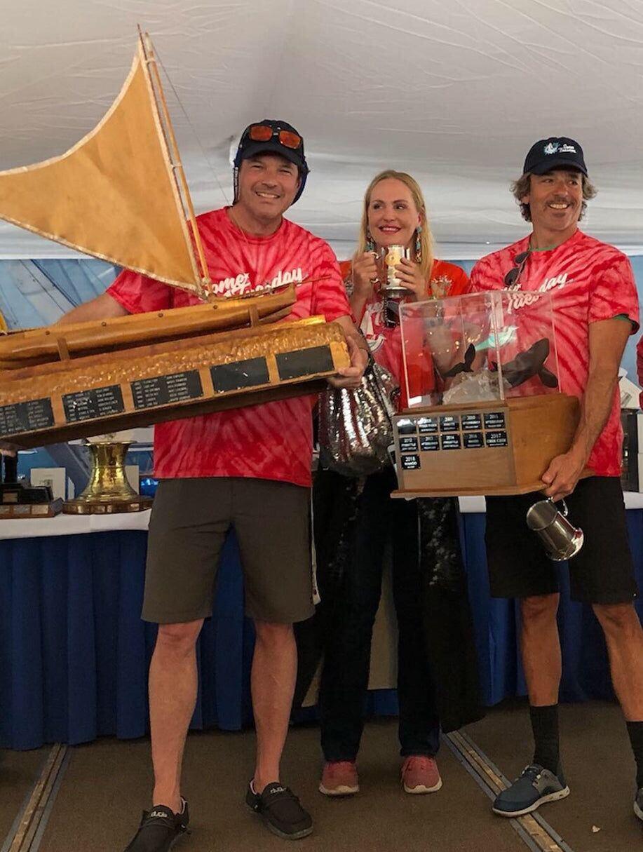 The crew of Some Tuesday in the cockpit, with a trophy cup on the helm seat