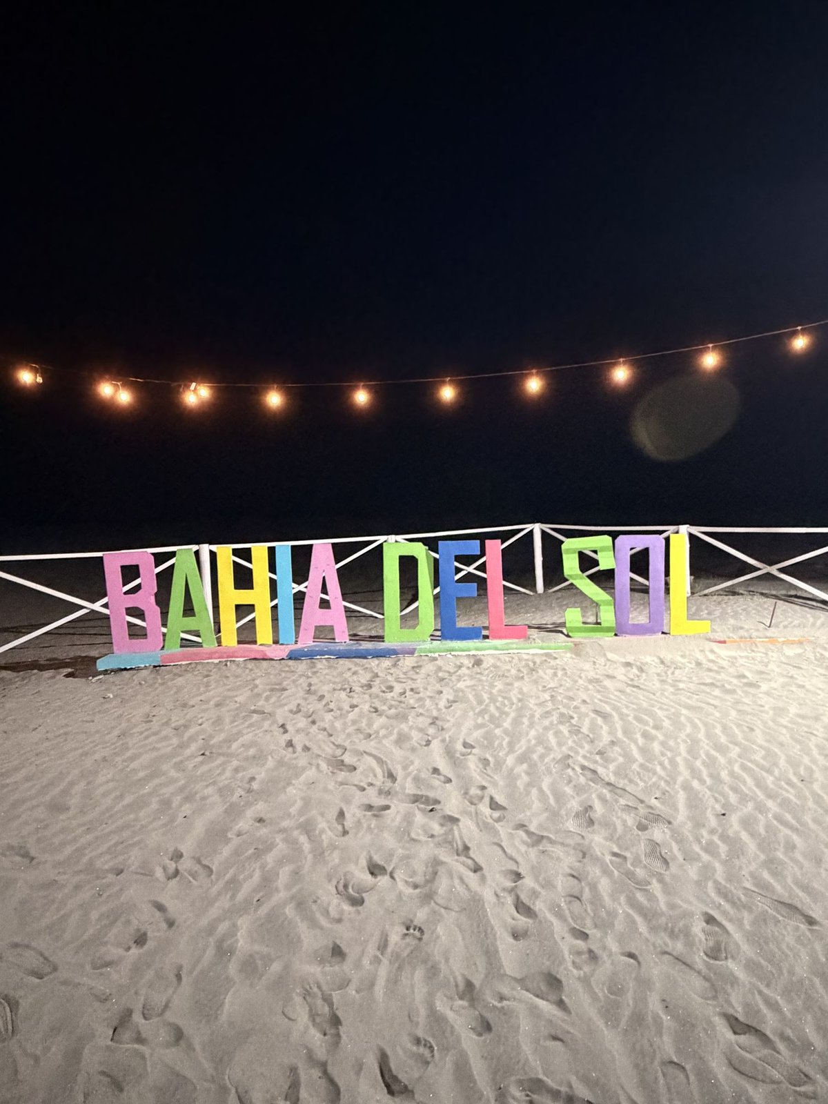 Colorful letters spelling Bahía del Sol on the beach at night