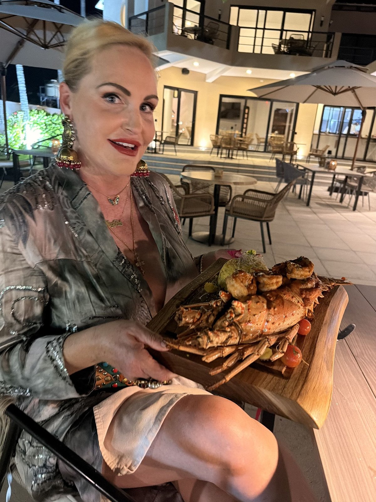 A seafood platter on a table, with boats in the marina beyond the railing