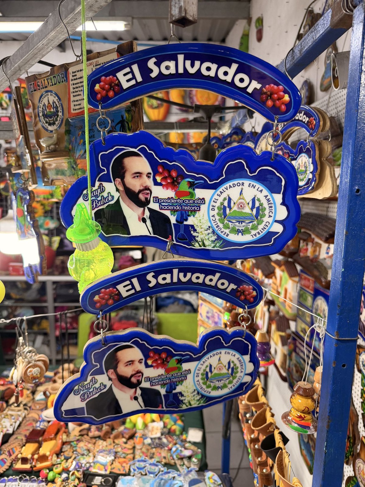 A wall hanging of President Bukele, with more Bukele pictures on the wall behind it