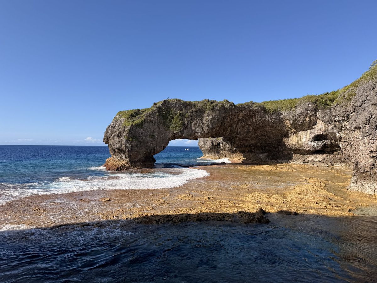 A limestone arch in the sea off Niue, with turquoise water showing through the opening