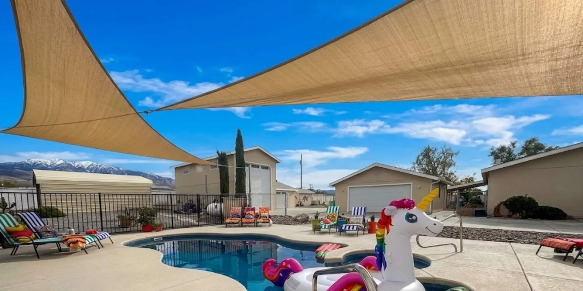 The pool and hot tub at Some Tuesday Ranch beneath shade sails, with the Spring Mountains in the distance