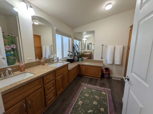 Bathroom with double vanity, soaking tub and green rug
