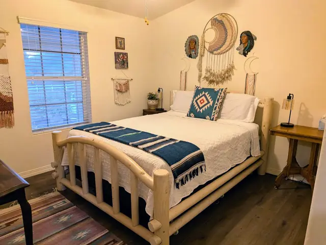 Bedroom with a log-frame queen bed and woven wall hanging
