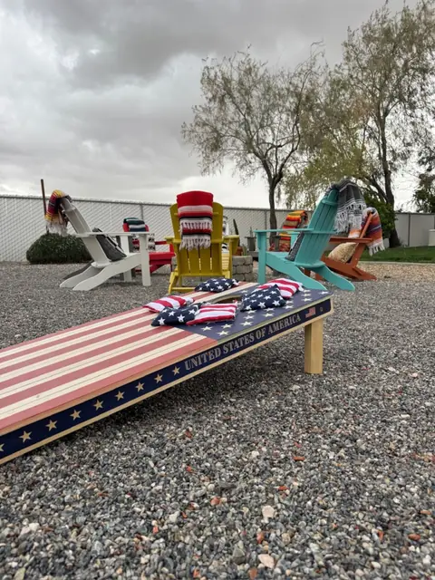 Stars-and-stripes cornhole board set up on the gravel