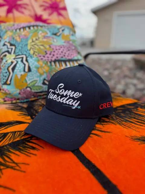 Some Tuesday crew cap resting on a bright beach towel