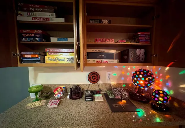 Cabinet stocked with board games, guidebooks and a disco light