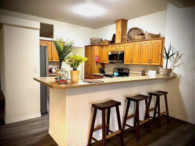 Granite kitchen bar with four stools open to the living space