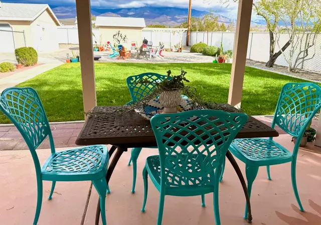 Covered patio dining table with turquoise chairs looking over the lawn
