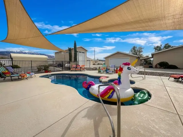 Free-form pool and spa under shade sails with the Spring Mountains beyond