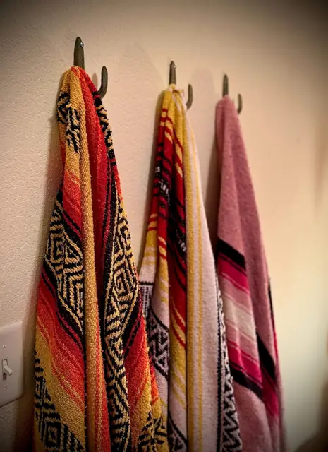 Striped serape blankets hanging on iron hooks by the door