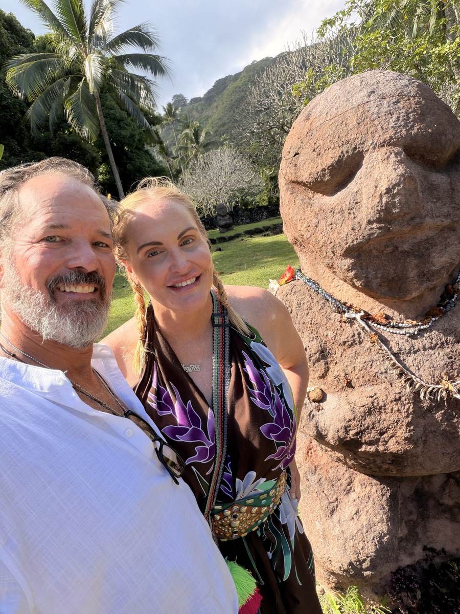 A carved wooden tiki in front of a thatched shelter on Tahiti